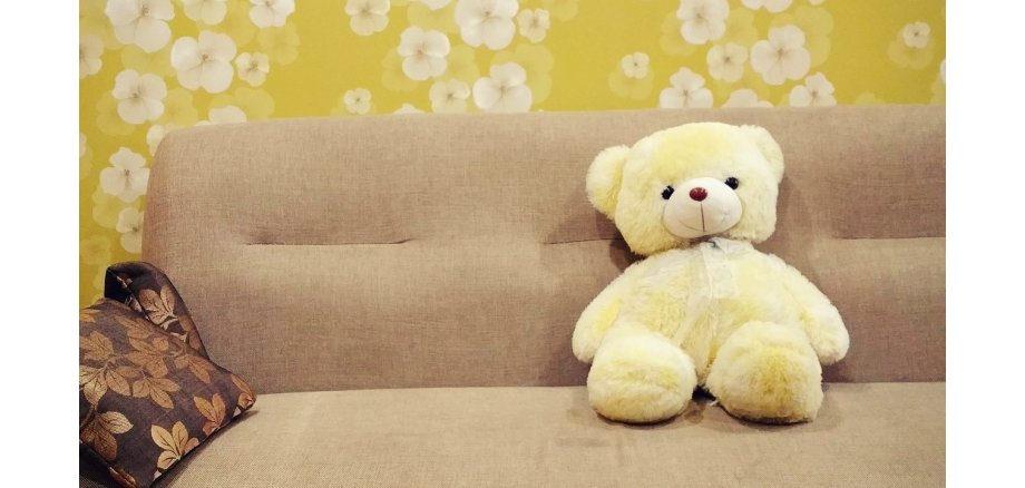 Auf dem Bild sieht man eine Couch mit einem Plüschteddybären