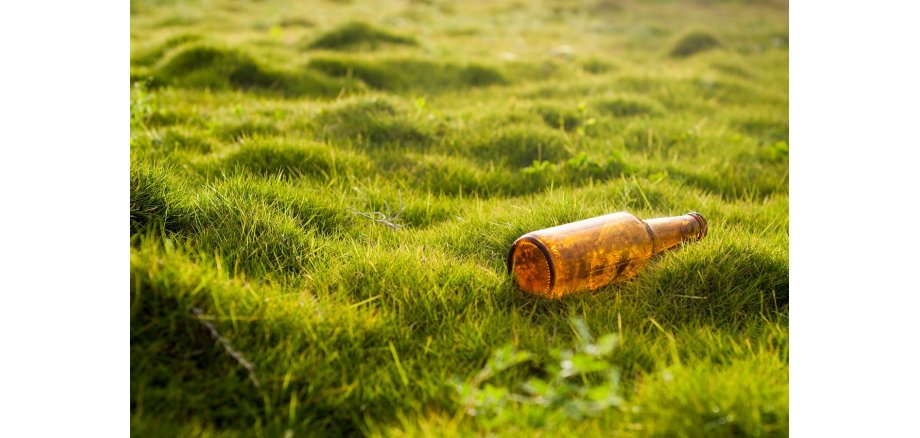 Umweltverschmutzung - Flasche liegt auf einer grünen Wiese